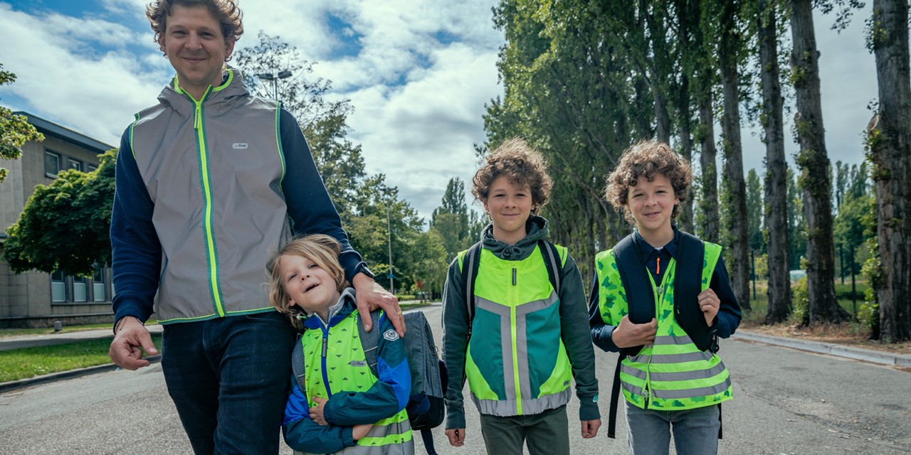 afbeelding van een vader en kinderen in fluor/reflector hesjes.