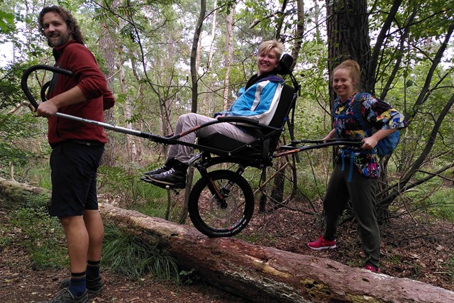 afbeelding van een wandelaar met een off-road rolstoel op een moeilijk begaanbaar pad.
