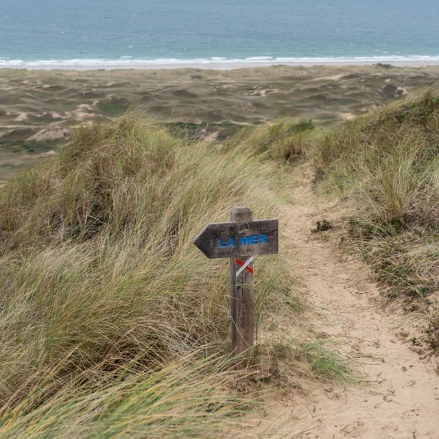 een bordje in de duinen dat naar de zee in Cotentin verwijst.