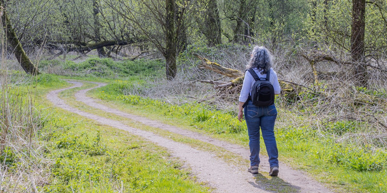 vrouw wandelt op een bospad.