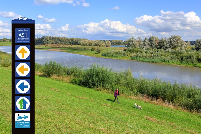 Routebord op de dijk met de rivier op de achtergrond