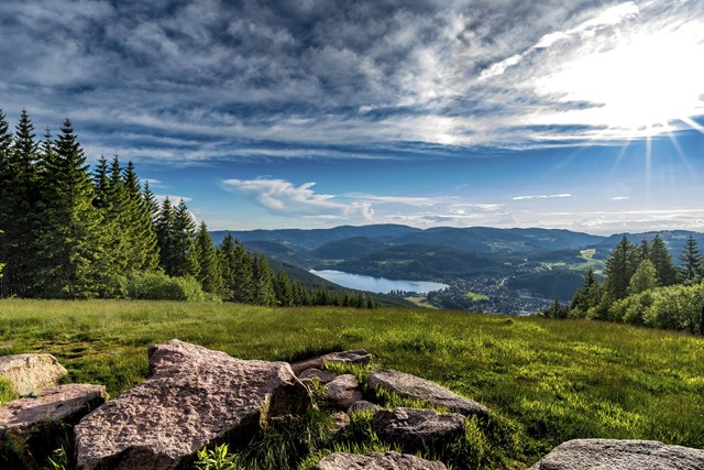Bergen met zon en een meer op de achtergrond