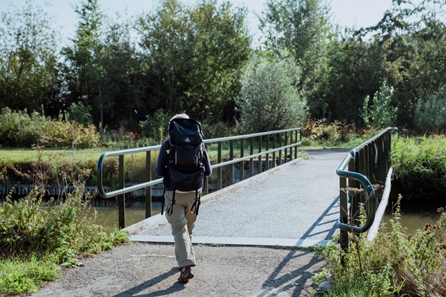 Wandelaar met grote rugzak op bruggetje
