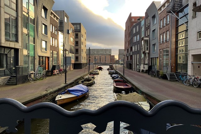 afbeelding van een gracht op Java-eiland, met nieuwbouwhuizen.