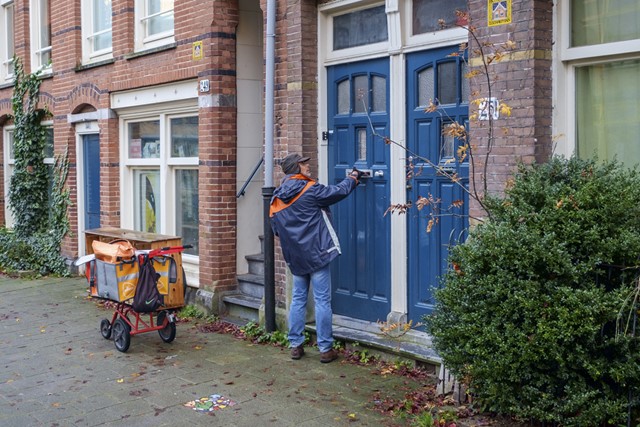 afbeelding van een postbode die zijn werk doet.