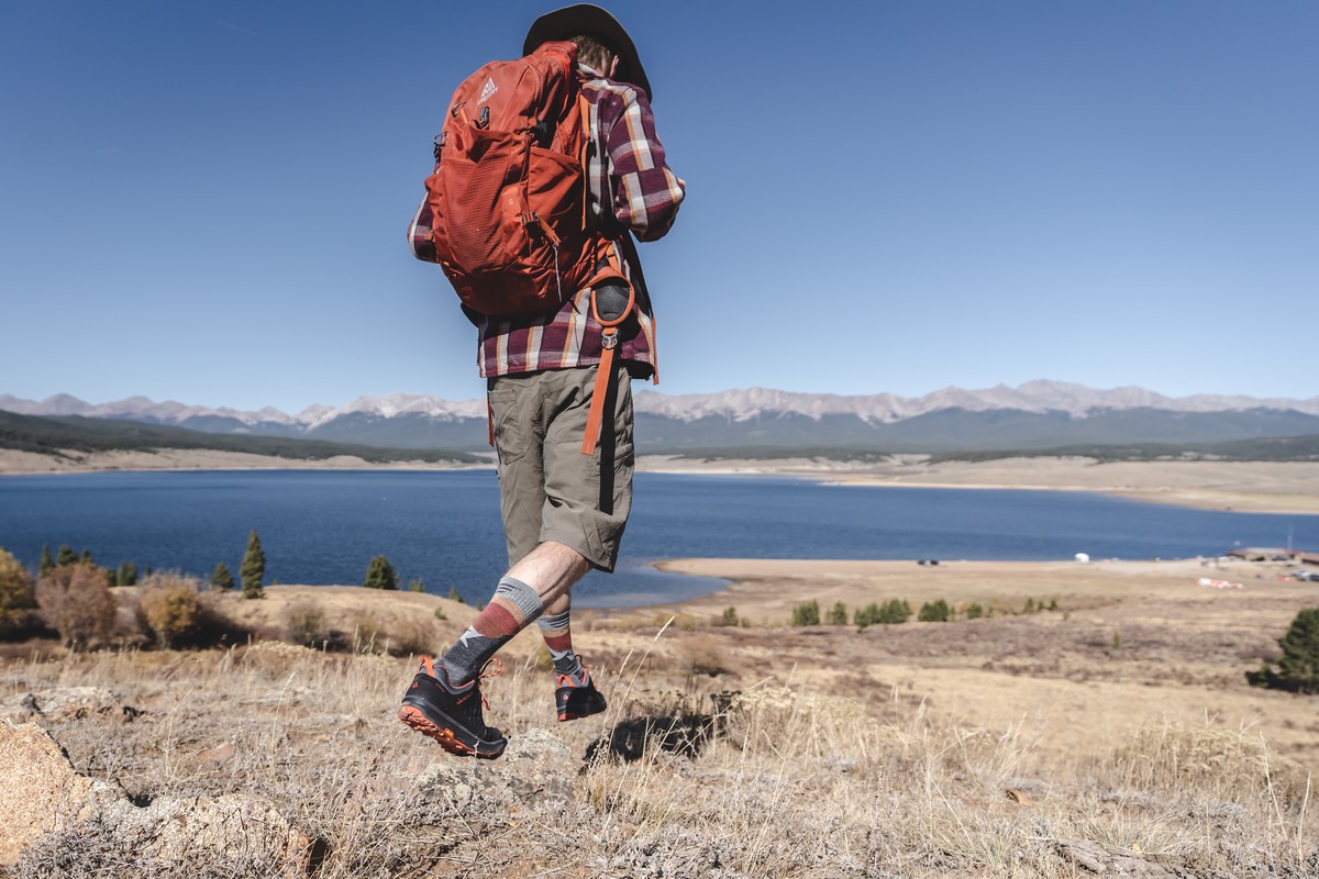afbeelding van een man met compressiekousen, die wandelt langs het water.