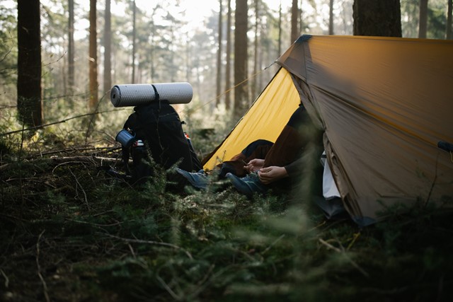 man trekt zijn schoenen aan in een tent in het bos