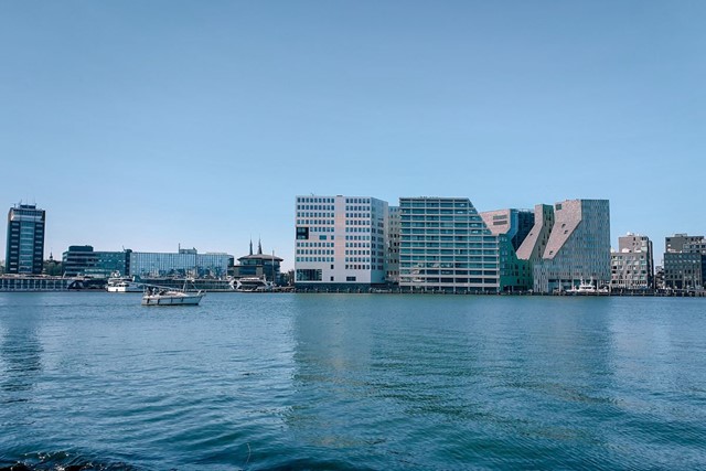 afbeelding van een moderne skyline aan het water, bij Oeverpark Amsterdam.
