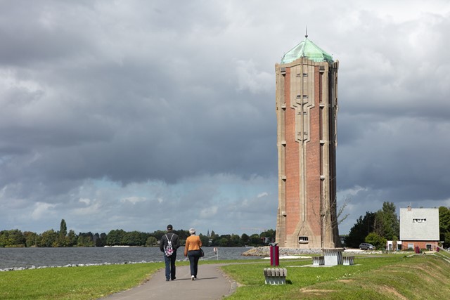 afbeelding van twee wandelaars die naar de watertoren toe lopen.