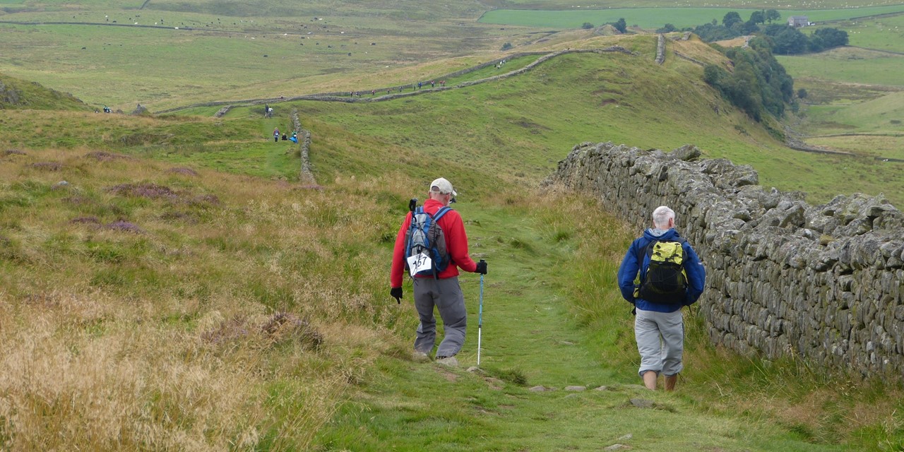 Wandelaars lopen langs een muurtje in het landschap van Groot-Britannië, Foto: Carin Rosseboom
