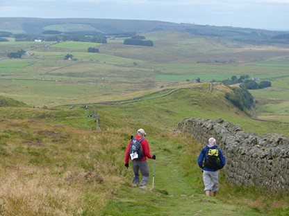 Wandelaars lopen langs een muurtje in het landschap van Groot-Britannië, Foto: Carin Rosseboom