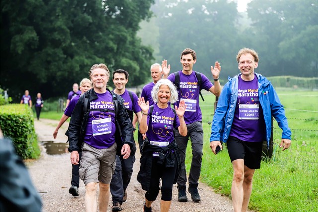 Groep volwassen wandelaars tijdens de Mega Wandel Marathon, zwaaiend