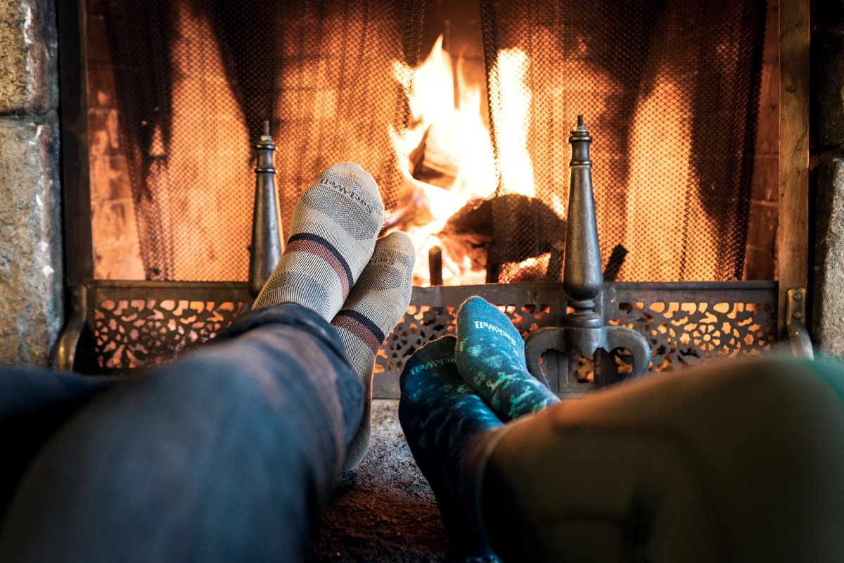 afbeelding van twee mensen die hun voeten opwarmen bij het vuur van de open haard.