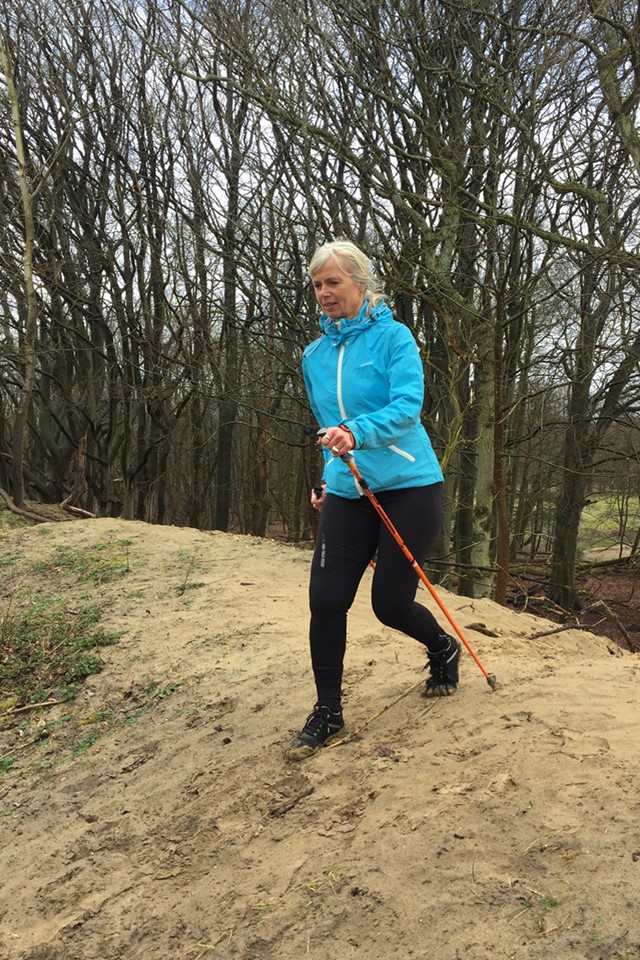 afbeelding van Mette die een heuvel af loopt met wandelstokken.