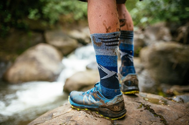 afbeelding van iemand die aan het hiken is bij een rivier, met compressiekousen aan.