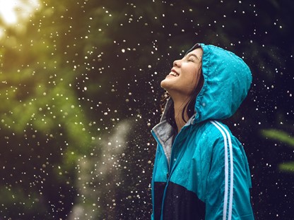 Vrouw met blauwe regenjas tijdens regenbui