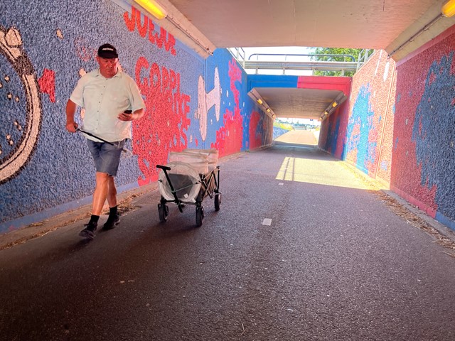 afbeelding van de Zwerfinator in actie met een kar met afval.