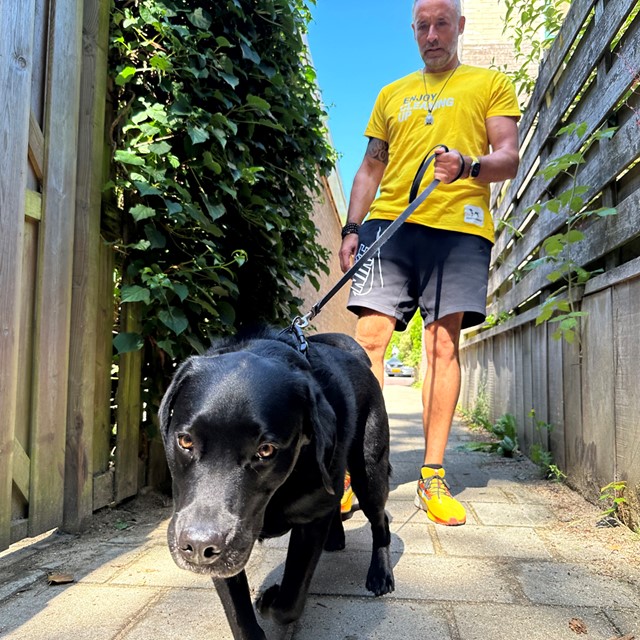 Alex laat labrador Bas uit, aan de lijn op straat.
