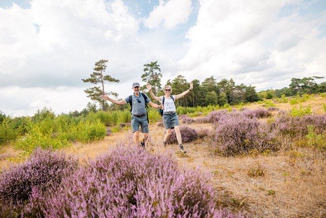 Twee blije wandelaars over de paarse heide tijdens Soester Wandelweekend.