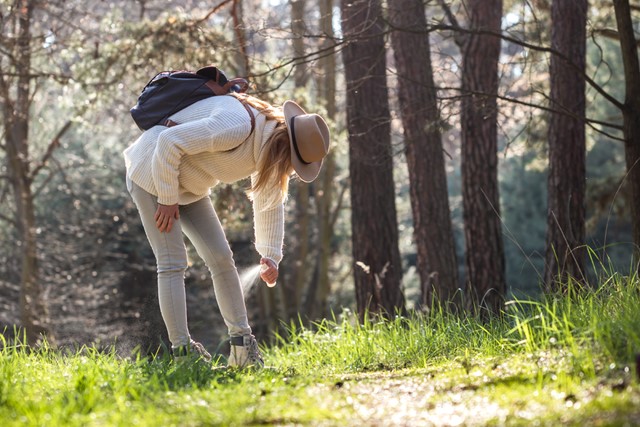 vrouw sprayt haar broek in tegen insecten.