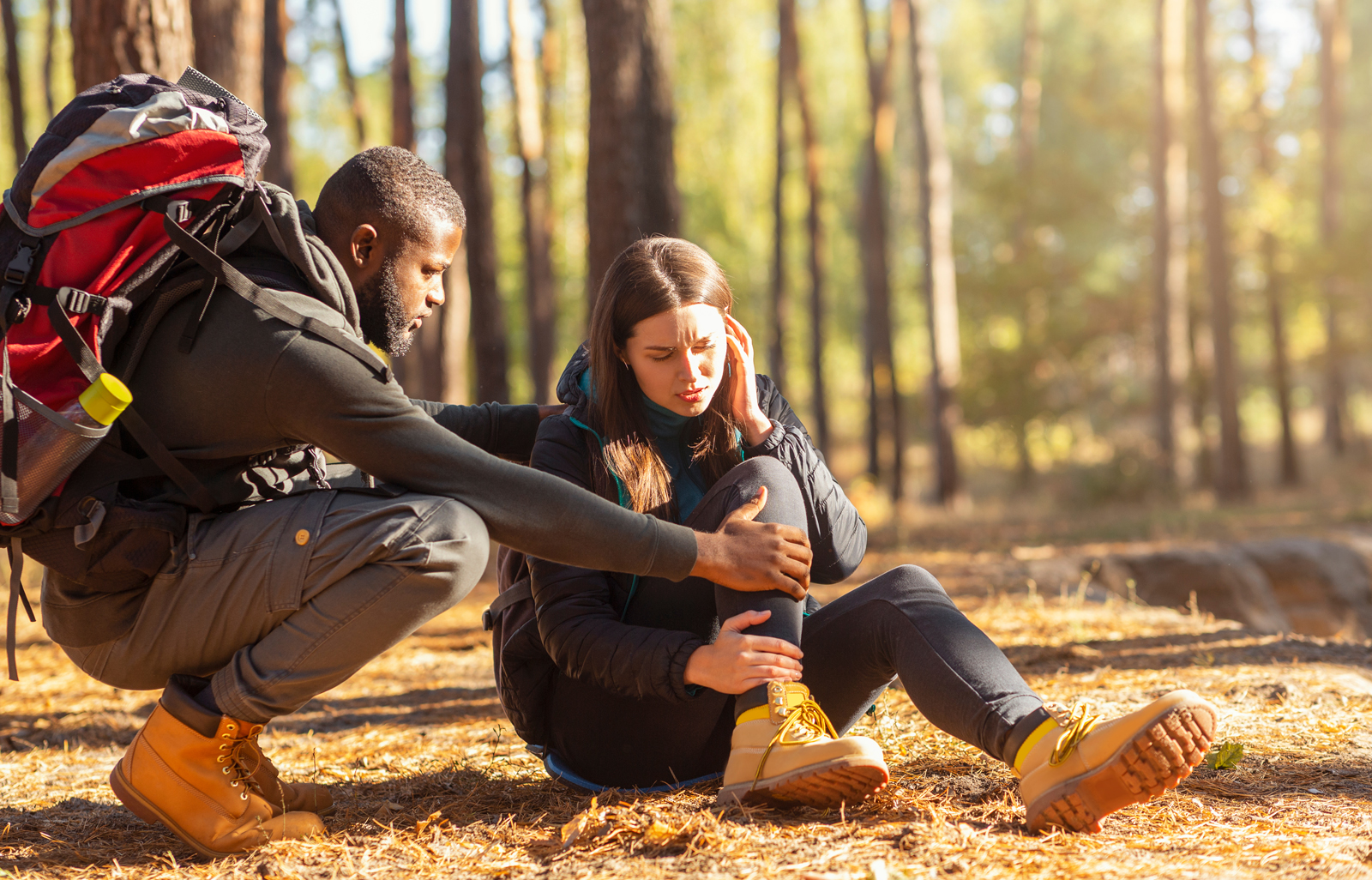 man helpt vrouw na een val in het bos.