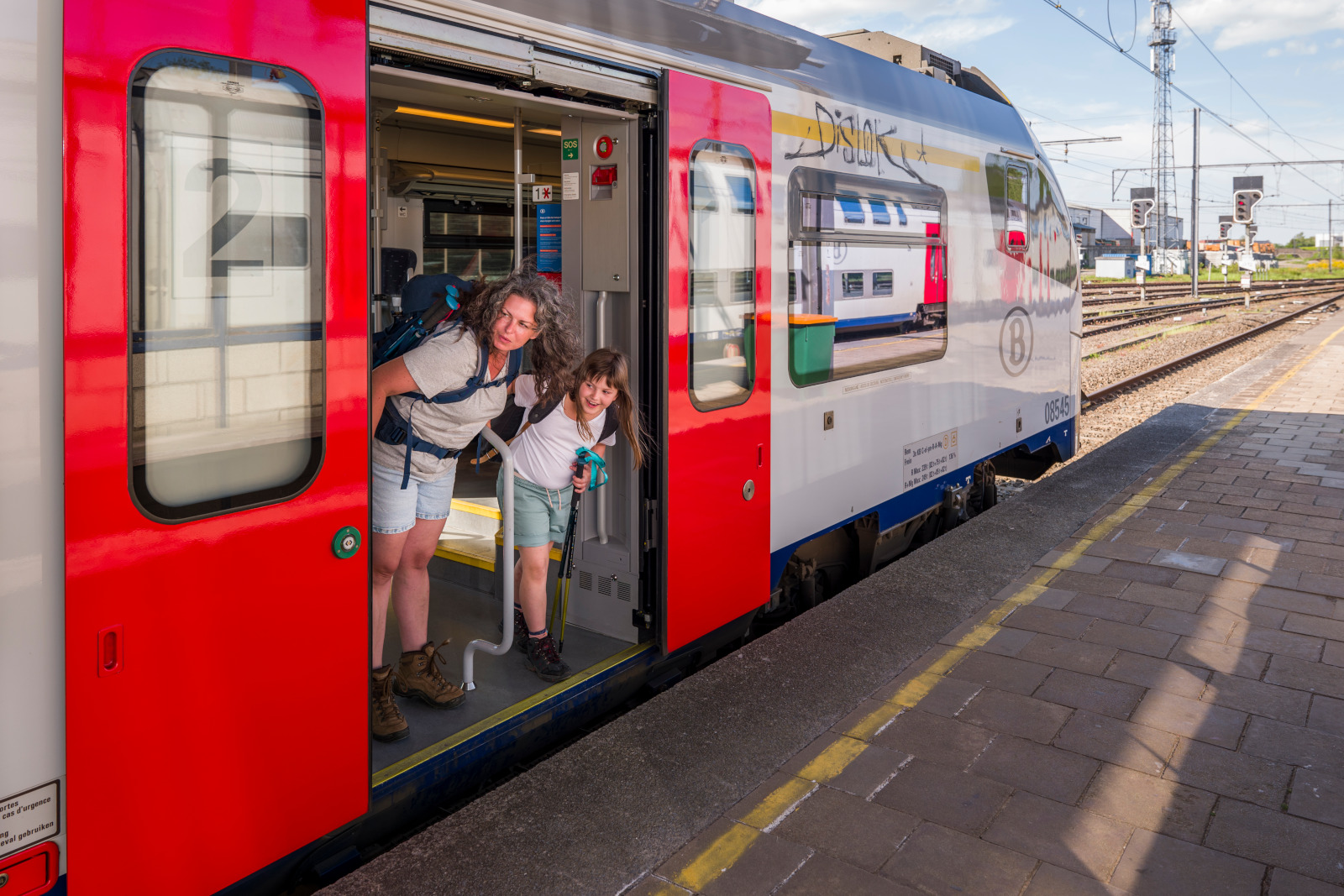 Een vrouw en een meisje kijken uit de trein met een rugzak op hun rug