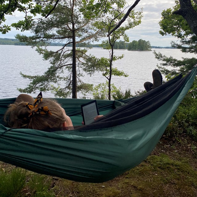 vrouw leest in een hangmat op trektocht.