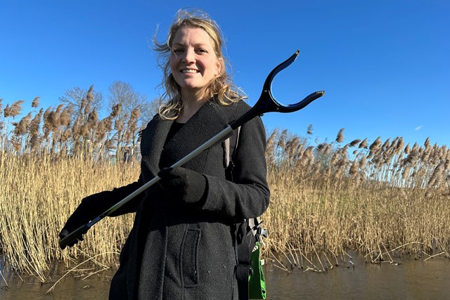 afbeelding van een vrouw met een afvalgrijper in haar handen.
