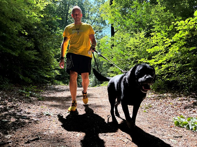 Alex wandelt in het bos met Bas, de plandellabrador.