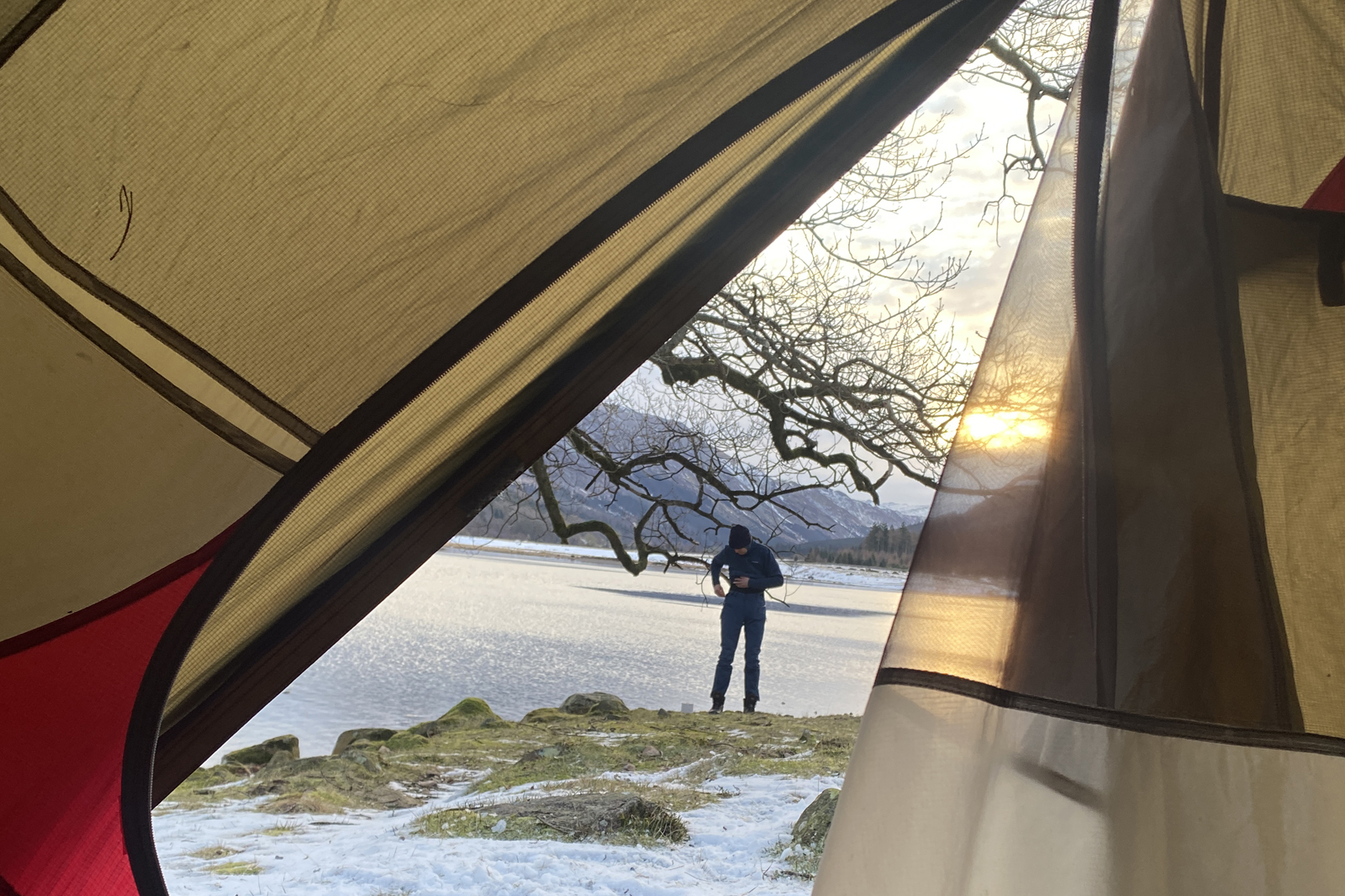 afbeelding  vanuit een tentje van iemand in een besneeuwd landschap.