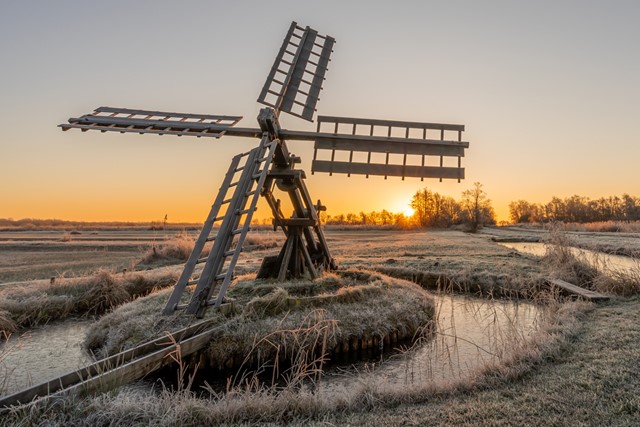 afbeelding van een molen in een winters landschap.